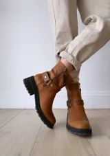 Bota de cuero color marrón con suela de goma negra, cierre lateral y pulsera desmontable con hebilla.