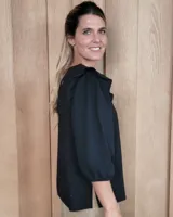 Remera blanca de algodón con cuello redondo, mangas tres cuartos abullonadas y detalle de volados en los hombros.