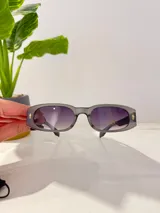 Lentes de sol con marco rectangular de acetato color gris translúcido y lentes degradadas de gris oscuro a transparente.