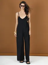 Mono largo negro de bretel fino con escote en V y detalle de flor en el pecho.