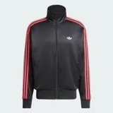 Campera deportiva Adidas modelo Firebird Loose Pinstripes, de color negro con diseño de rayas diplomáticas sutiles. Cuenta con cuello alto, cierre frontal completo, bolsillos laterales y bandas tricolor en rojo, blanco y negro a lo largo de las mangas. Incluye el logo del trifolio bordado en el pecho.