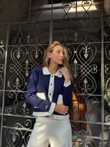 Chaqueta tejida en hilo color azul marino con detalles en blanco en cuello, bolsillos y puños.