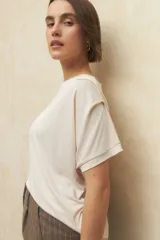 Remera color beige de manga corta con cuello redondo y detalle de pliegues en los hombros.