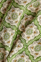 Vestido túnica corto de viscosa con estampado geométrico en tonos verdes y crudo, escote en V pronunciado tanto en el frente como en la espalda, mangas tres cuartos y diseño oversized.