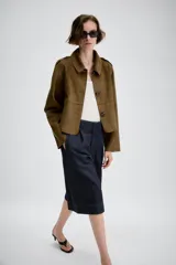 Chaqueta corta de efecto ante en color marrón, con cuello solapa, manga larga y trabillas en los hombros. Presenta cierre frontal con botones y bolsillos delanteros de doble vivo.