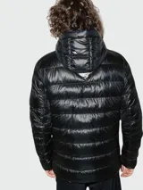 Campera acolchada con capucha de la marca Canada Goose, confeccionada en material brillante de color negro. Presenta cierre frontal, bolsillos laterales y el distintivo parche del logo en la manga.