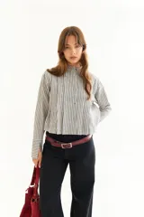 Blusa de algodón a rayas verticales, con cuello mao, cierre frontal de botones, tablas delanteras que generan volumen y puños largos con abertura.