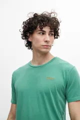 Remera color mostaza de corte clásico, con cuello redondo y logo pequeño estampado en el pecho.