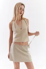 Top bordó de punto con lurex, escote en V profundo estilo halter y diseño sin mangas.