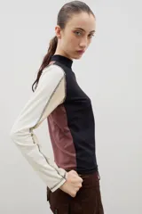 Remera de cuello alto y manga larga en color crudo, con costuras a la vista en contraste de color marrón.