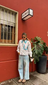 Camisa de manga larga con estampado cuadrillé en tonos beige y blanco, con cuello camisero y bolsillo frontal adornados con volados en color turquesa.