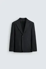 Blazer relaxed fit de estructura color gris, confeccionado en tejido con algodón, cuello con solapas de muesca, manga larga con botones en los puños y bolsillos de plastrón en la cadera.