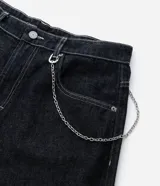 Pantalón de jean estilo baggy balloon, de corte holgado con volumen en las piernas y cintura fija con trabillas. Presenta costuras a contratono y detalle de cadena metálica lateral.