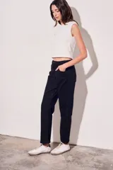 Pantalón de jean negro, de corte recto y tiro medio. Presenta bolsillos delanteros y traseros, y una hilera de botones metálicos a lo largo de la costura lateral.