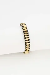 Pulsera de diseño étnico con eslabones metálicos dorados entrelazados con hilo de algodón negro, creando un patrón geométrico.