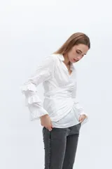 Camisa blanca de algodón con diseño cruzado y mangas largas con volados.