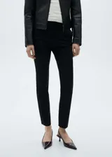 Pantalón negro de corte skinny, tiro medio y largo a la altura del tobillo.