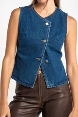 Chaleco de denim azul con cierre cruzado con botones metálicos.