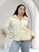 Campera color crudo de pana con cuello, puños y ruedo de corderito. Tiene cierre frontal y corte recto.