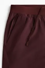 Short deportivo bordó fabricado en tejido funcional con tecnología DryMove, cintura elástica con cordón ajustable oculto y aberturas laterales en el bajo.