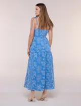 Vestido midi color azul con bordado broderie floral en tono blanco, escote recto con tirantes finos de lazo para anudar, corte ajustado en la cintura y falda escalonada holgada con bolsillos laterales.