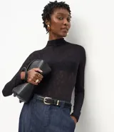 Blusa de encaje negro con cuello alto y mangas largas, de corte ajustado y diseño con transparencias.