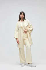 Tapado de largo medio abierto con cuello, confeccionado en lana fina sin teñir con detalles de terminación envivados en los bordes y mangas tres cuartos.