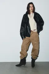 Jeans tiro medio, corte baggy balloon, color marrón claro con estampado animal moteado en tono más oscuro. Presenta bolsillos laterales, bolsillos cargo con solapa en las piernas y bolsillos de plastrón en la espalda. El bajo es ajustable con botón a presión.