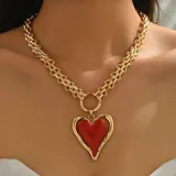 Collar dorado de eslabones gruesos con dije de corazón rojo.