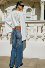 Jeans de tiro alto y corte recto de pernera larga, con diseño clásico de cinco bolsillos y costuras en contraste. Cierre frontal con cremallera y botón metálico.