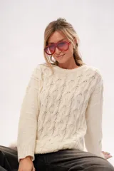 Sweater de punto color crema con cuello redondo y mangas largas.