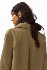 Campera camisera corta de sarga de algodón color verde militar, con cuello camisero, cierre frontal de botones oscuros y dos amplios bolsillos delanteros de parche.