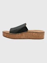 Sandalia tipo slide de Hush Puppies con capellada de cuero negro y banda elástica lateral. Presenta una suela de plataforma alta con acabado de corcho y base de caucho.