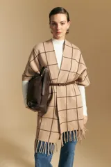 Poncho abierto de tejido de punto con diseño de cuadros grandes en contraste. Presenta un patrón reversible en tonos negro y marrón, con un estilo envolvente y versátil.