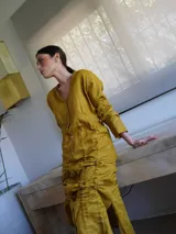Vestido corto de lino rojo con escote en V, mangas largas y sistema de jaretas ajustables con cordones frontales para fruncir y regular el largo.