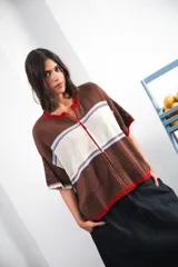 Remera de punto con diseño retro de bloques de color en marrón, crema y celeste. Presenta cierre frontal, cuello redondo, mangas cortas y tejido calado en la parte inferior. Incluye detalle de logo en relieve en el frente.