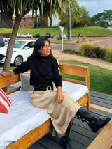 Falda midi de satén en color negro, con corte al bies y caída fluida que se ajusta suavemente a la silueta.