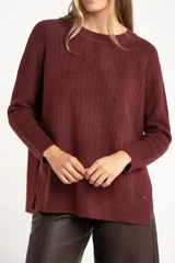 Sweater de punto con textura acanalada, cuello redondo y mangas largas. Presenta un diseño de calce holgado con ruedo redondeado y aberturas laterales.
