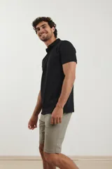 Remera tipo polo de manga corta, color negro, con cuello clásico y cierre frontal de botones.