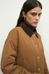 Campera color verde militar con cuello de pana marrón, bolsillos con solapa y botones metálicos. Interior forrado con tela satinada capitoneada.