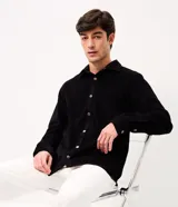 Camisa de terciopelo cotelé color negro, de corte clásico con cuello solapa, manga larga, cierre frontal de botones y un bolsillo aplicado en el pecho.