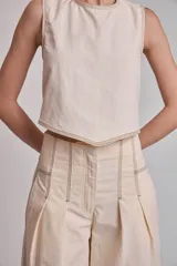 Blusa crop top negra sin mangas con cuello redondo y pespuntes blancos contrastantes.