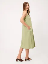 Vestido midi sin mangas de corte recto y holgado, color beige, con cuello redondo y bolsillos laterales.