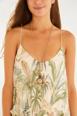 Vestido largo de poliéster con forro de viscosa, de corte amplio y silueta fluida en capas, con estampado tropical de palmeras en tonos verdes y tostados sobre fondo beige, escote en V y tirantes finos.