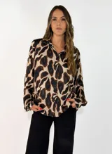 Camisa de manga larga con cuello camisero y cierre frontal de botones, confeccionada en tela fluida con estampado animal print en tonos marrones y negros.