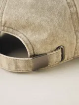 Gorra de béisbol color gris oscuro con efecto lavado o acid wash, visera curva y panel frontal estructurado. Presenta una pequeña etiqueta negra cosida en el lateral trasero.
