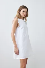 Vestido corto blanco de lino, sin mangas, con volados en los hombros y escote redondo.