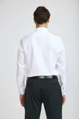 Camisa de vestir blanca de corte clásico, con cuello rígido, cierre frontal de botones y mangas largas con puños abotonados.