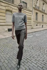 Jersey de cuello redondo color gris, con abalorios joya en el cuello, manga corta y tejido efecto cepillado. Cierre en la espalda con abertura y botón.