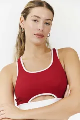 Top deportivo negro con contorno y tirantes blancos, con abertura en el centro del pecho.